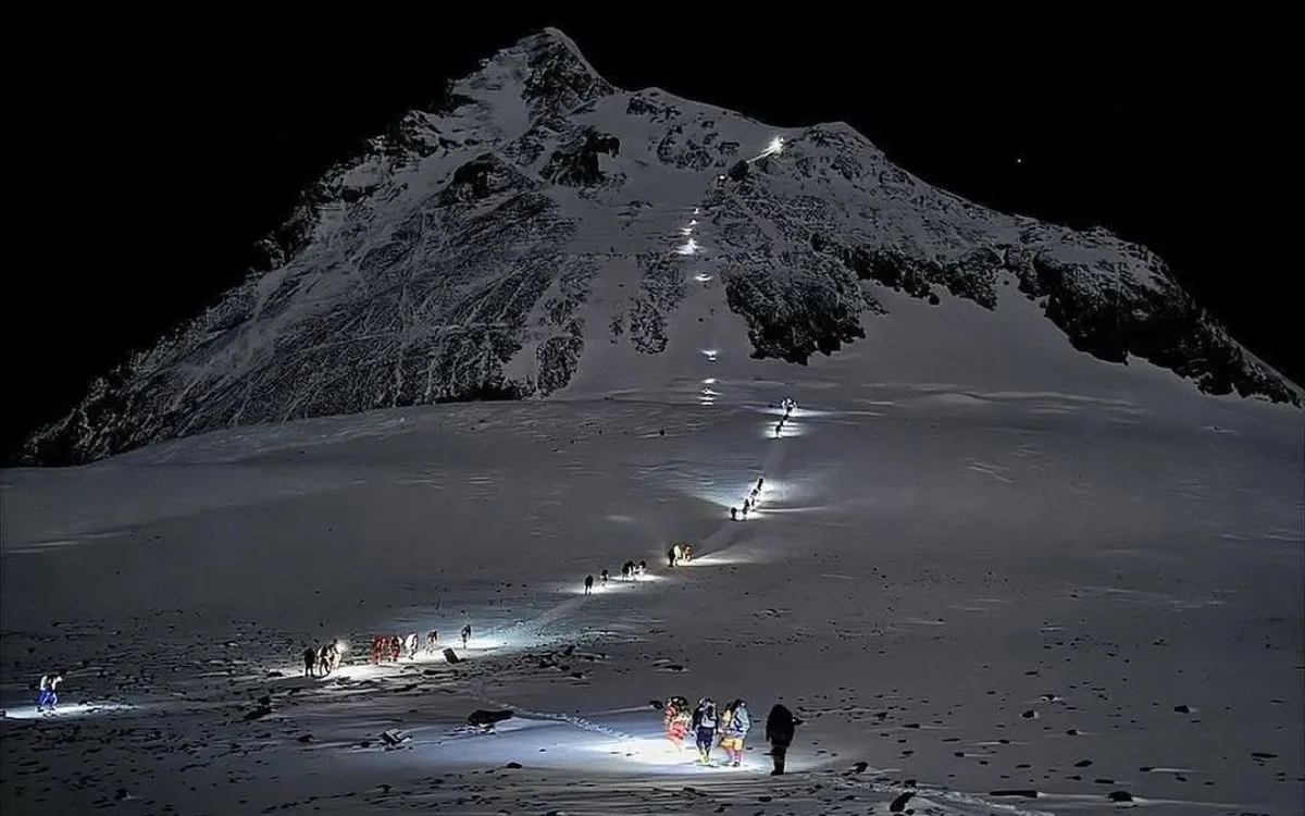 Night mountaineering expedition with headlamps ascending snowy slopes between Everest camps