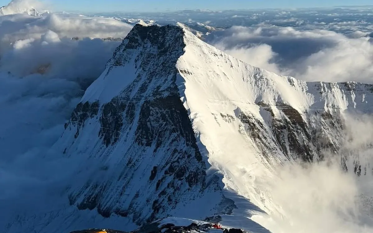 Snow-covered mountain peak with climbing tents at high altitude camp in Everest region