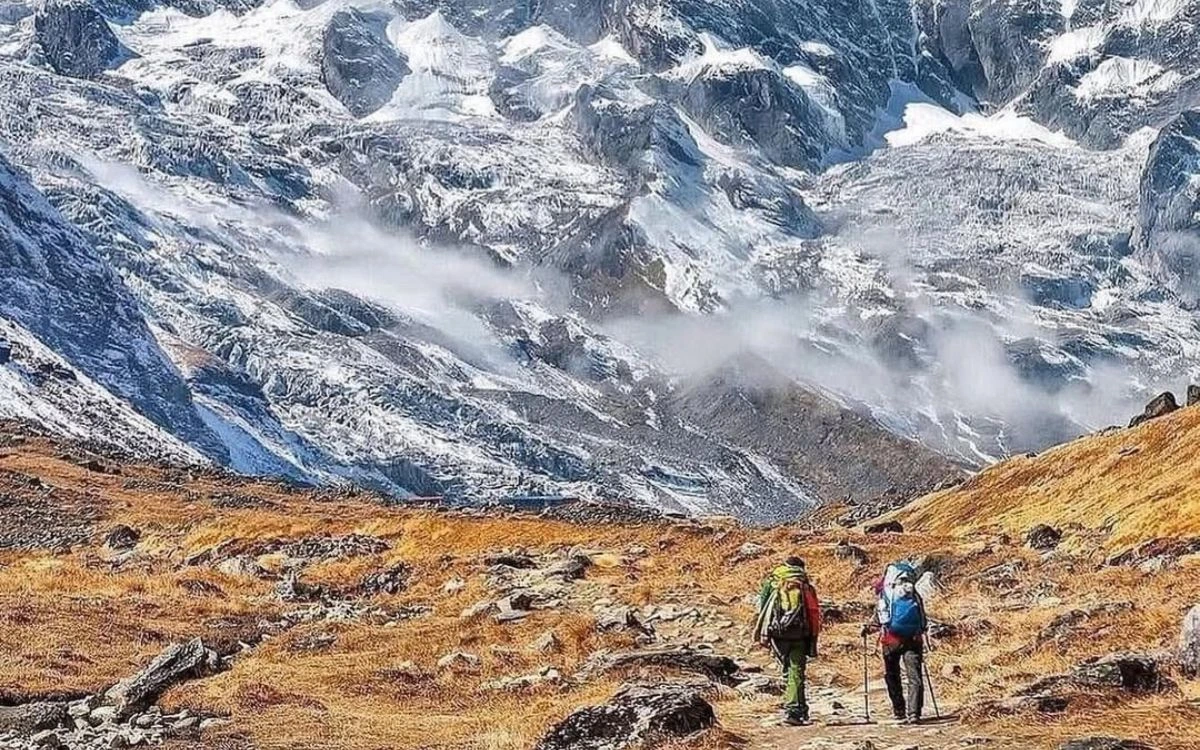 Hikers trekking toward snow-covered Annapurna mountain in Nepal Himalayas