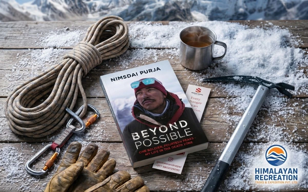 The book "Beyond Possible" by Nimsdai Purja surrounded by climbing gear, a rope, gloves, an ice axe, and a hot mug on snowy wood.