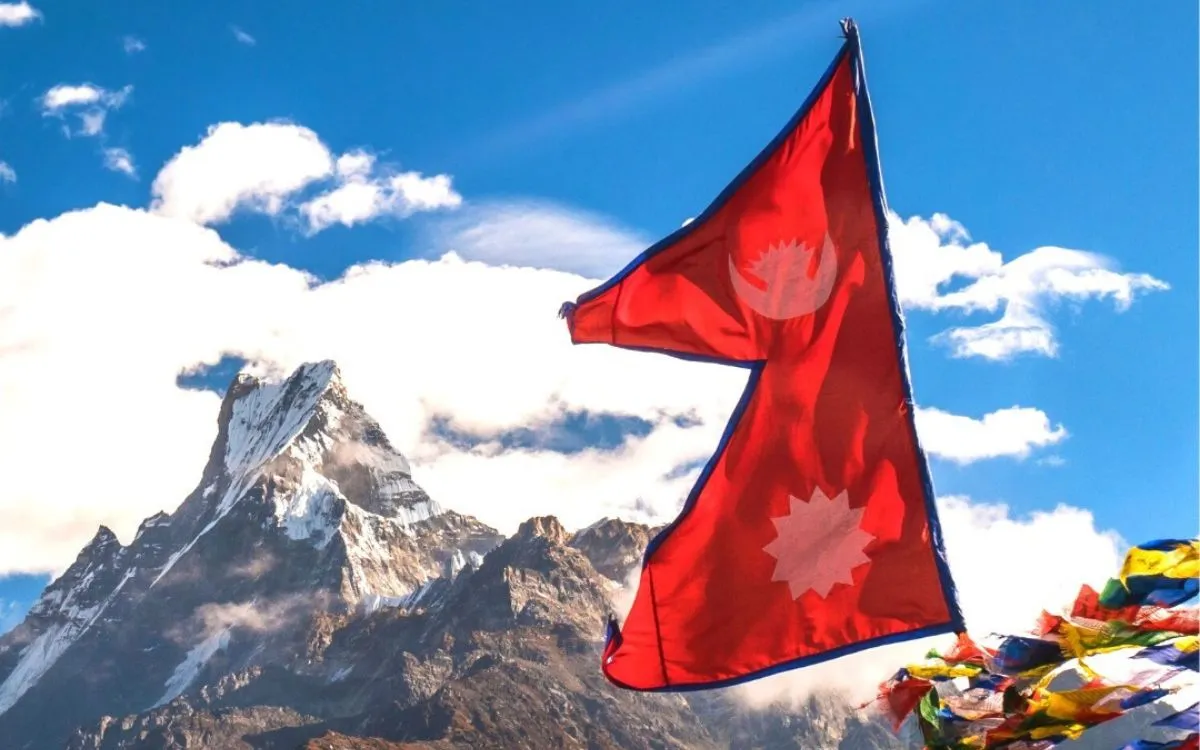 Nepal flag flying against mountain backdrop with prayer flags