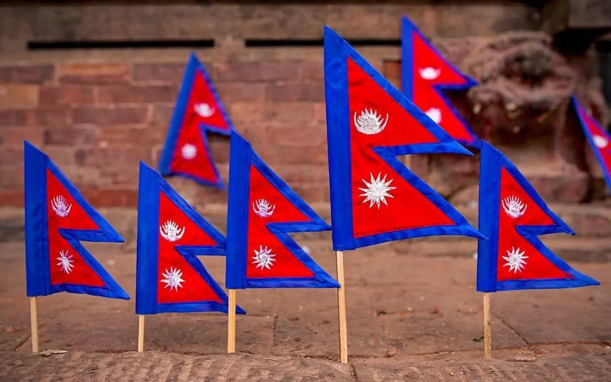 Multiple small Nepal flags on wooden sticks arranged on brick surface
