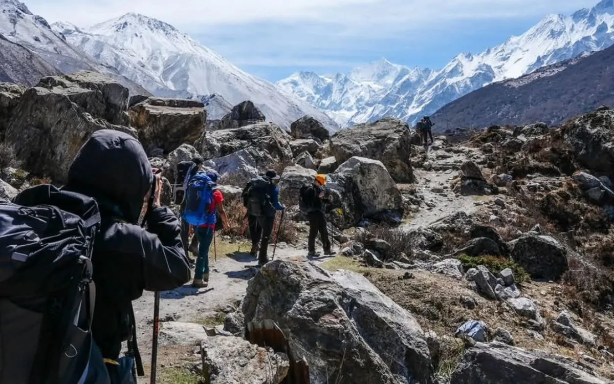 Trekkers hiking rocky trail with Langtang peaks in background