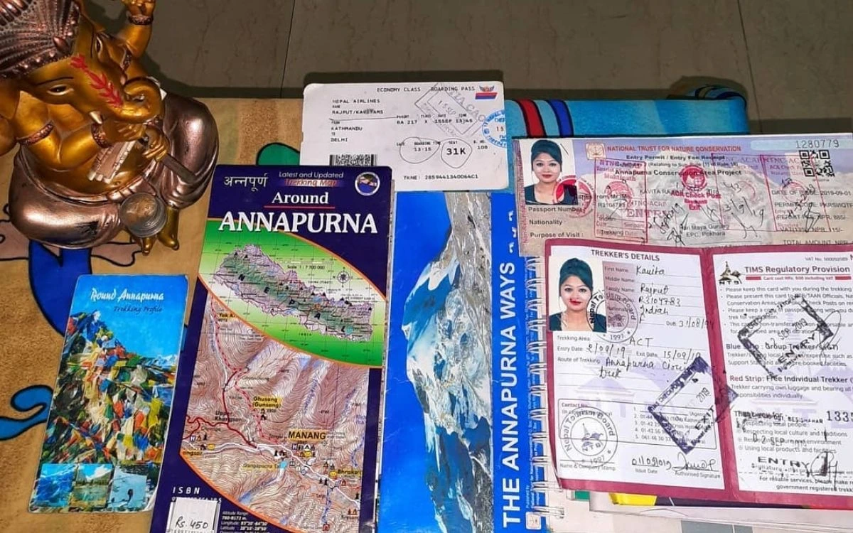 Nepal trekking permits, guidebook, and documents arranged on table with decorative statue