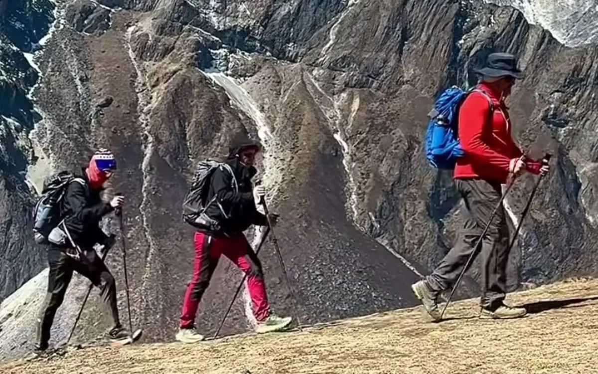 Group of trekkers hiking across rocky mountain terrain with trekking poles