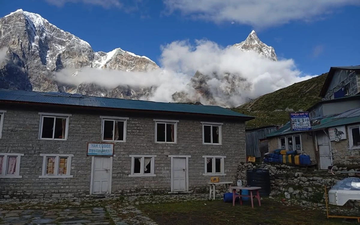 Stone teahouse lodge with snow-capped peaks emerging from monsoon clouds in Nepal