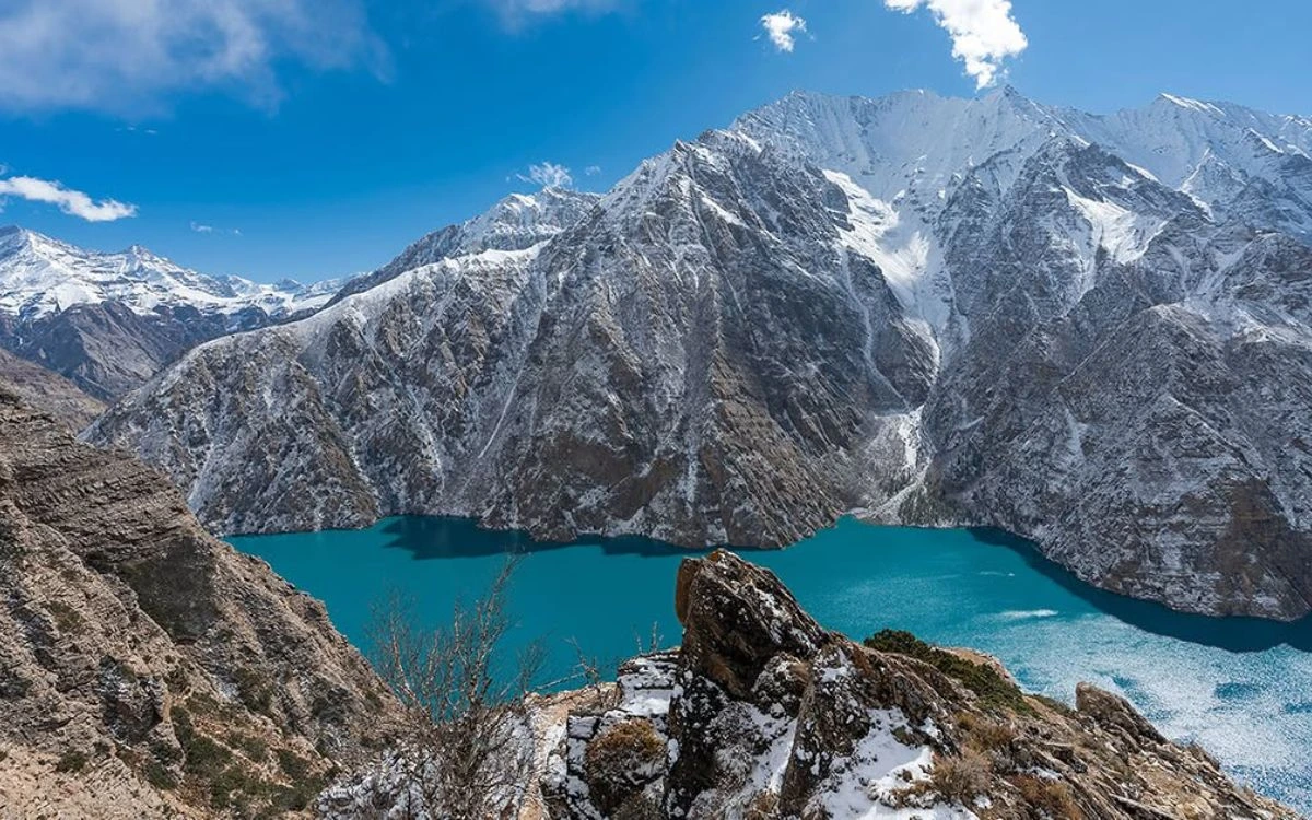 Turquoise Phoksundo Lake surrounded by snow-dusted cliffs in Upper Dolpo, Nepal