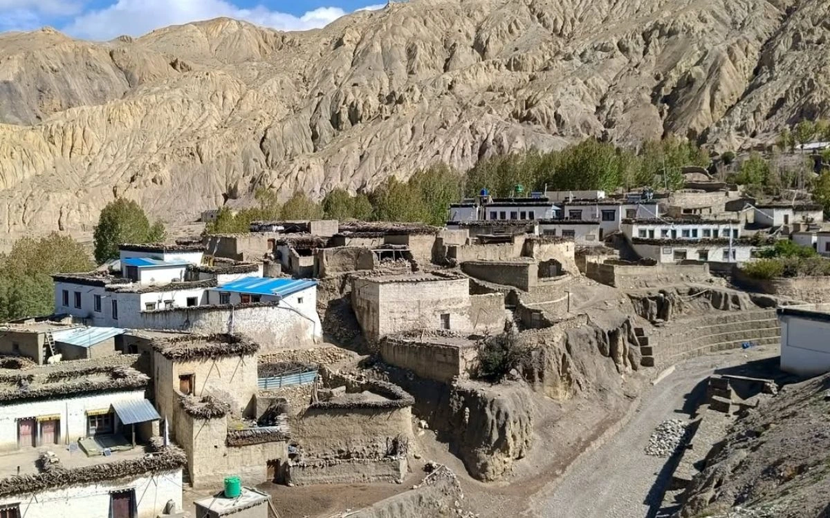 Traditional mud-brick village with flat rooftops against eroded desert hills in Upper Mustang