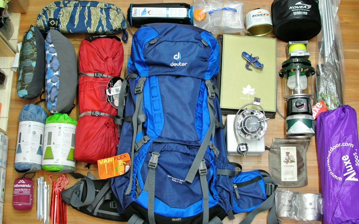 Complete trekking gear laid out including backpack, sleeping bag, and camping equipment