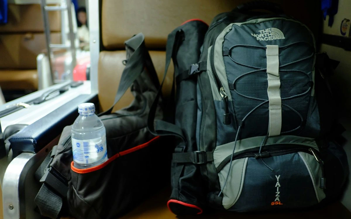 Trekking backpack with water bottle attached resting indoors before trek