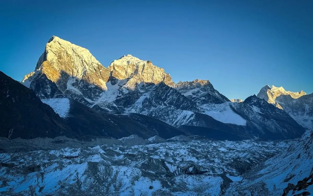 Snow-covered Himalayan peaks with golden sunrise light against blue sky