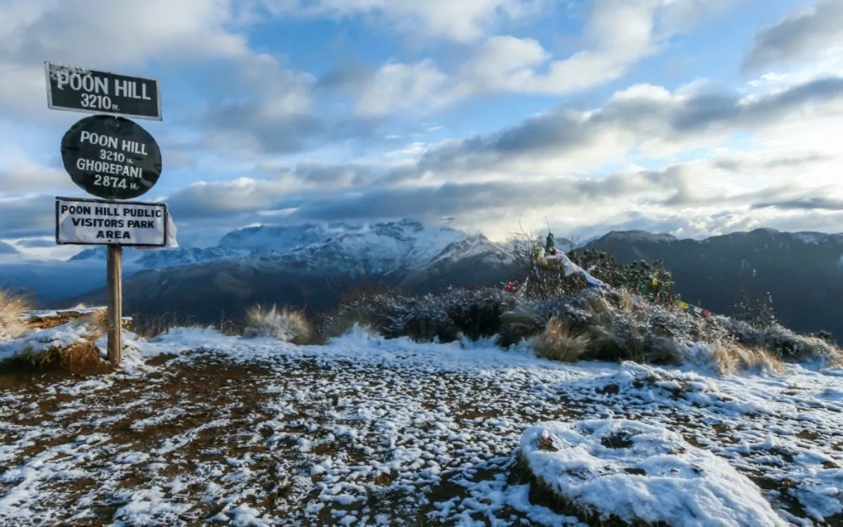 Poon Hill summit sign at 3210m with snow-dusted mountains in background