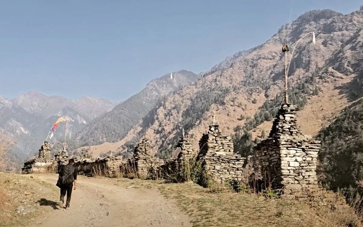 Stone chortens and prayer flags on mountain trail with distant peaks