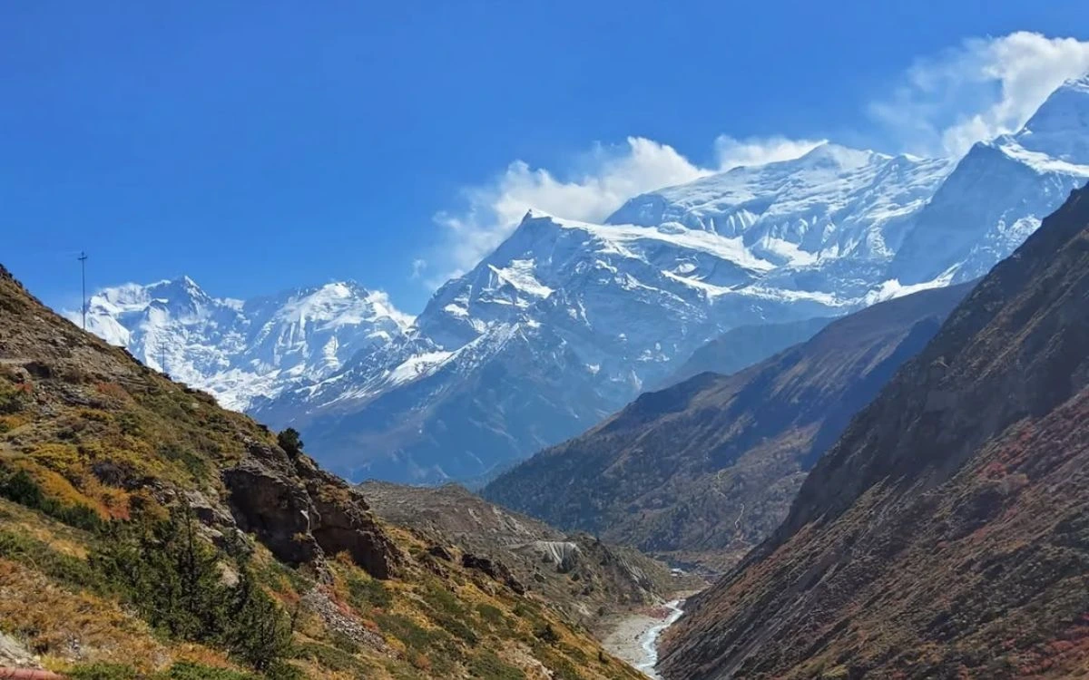 Valley view from Yak Kharka with a glacial river and towering snow-capped Annapurna peaks