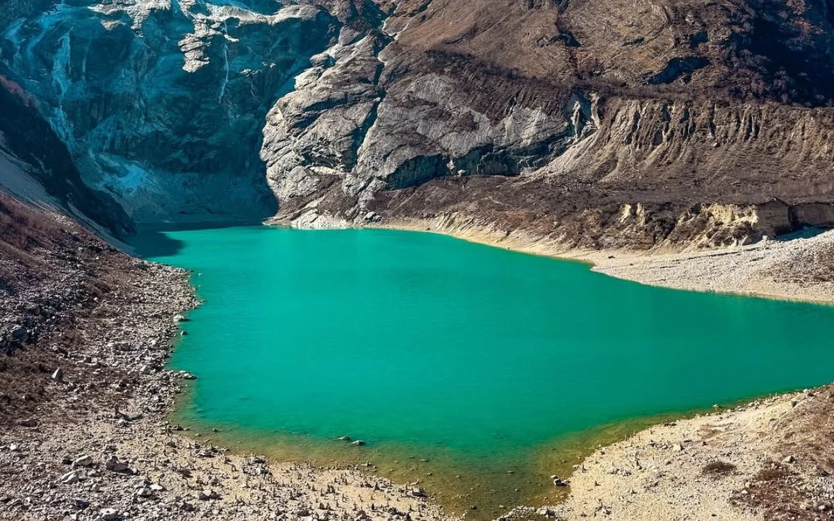 A pristine, turquoise alpine lake surrounded by steep, rocky mountain slopes.