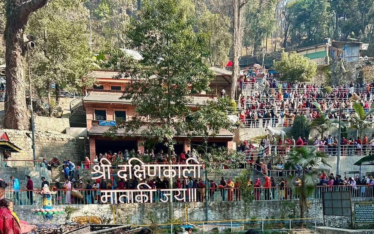 Crowds of devotees gathering at the entrance of Dakshinkali Temple amidst lush trees.