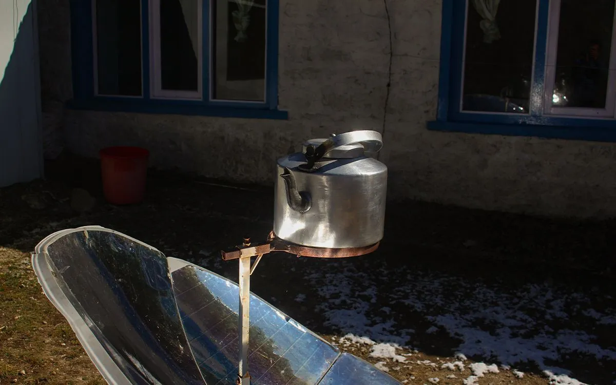 Metal kettle heating on solar cooker outside mountain teahouse on Manaslu Circuit trek