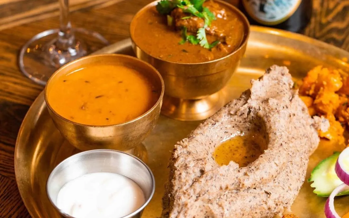 Traditional Nepali food plate with dal, curry, flatbread and local beer bottles
