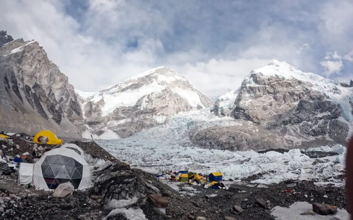 Mount Everest Base Camp expedition tents scattered across rocky moraine with glacier and mountains