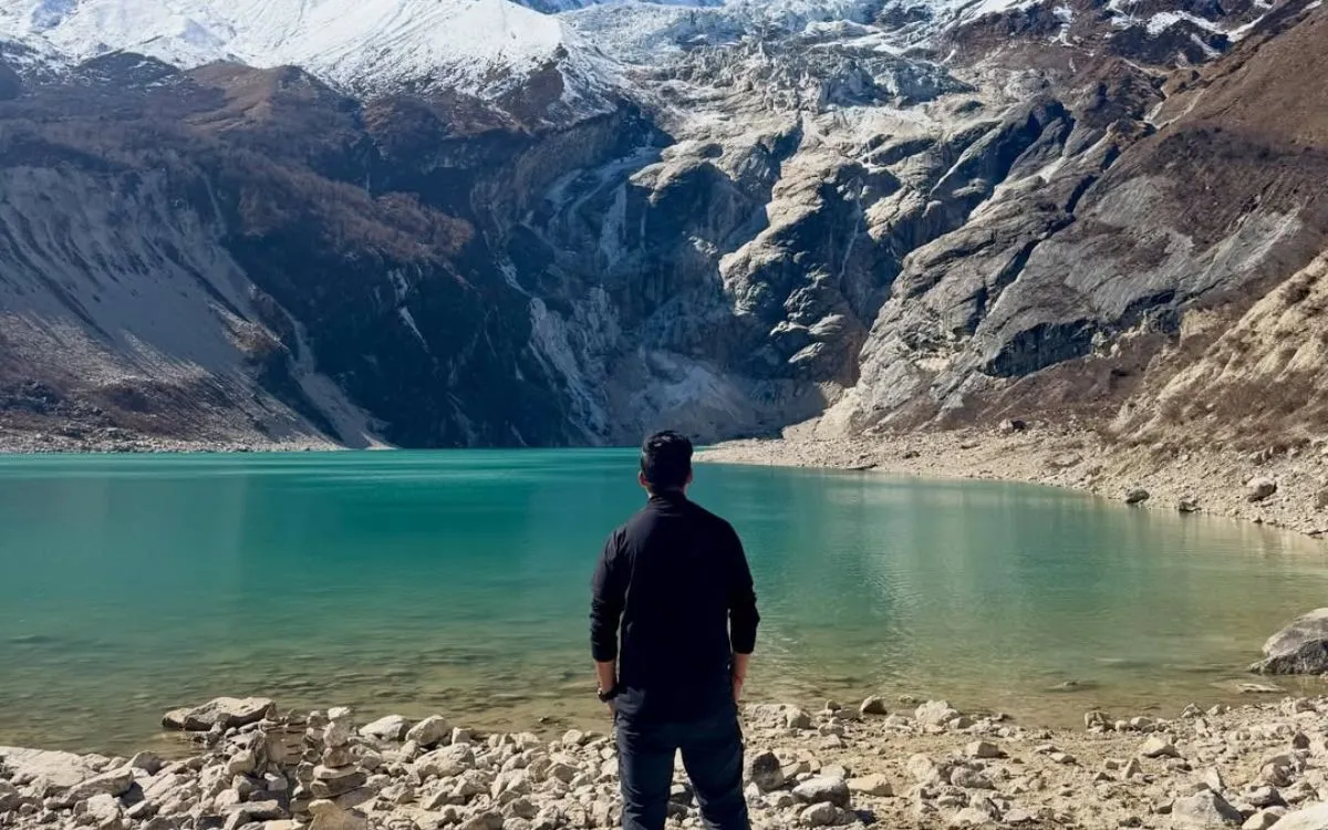 Hiker at turquoise glacial lake with Manaslu mountain backdrop