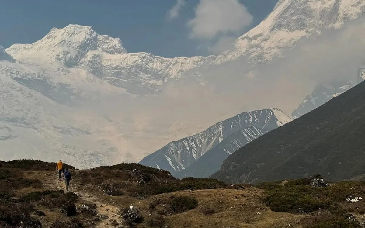Hikers on mountain trail beneath Himalayan peaks