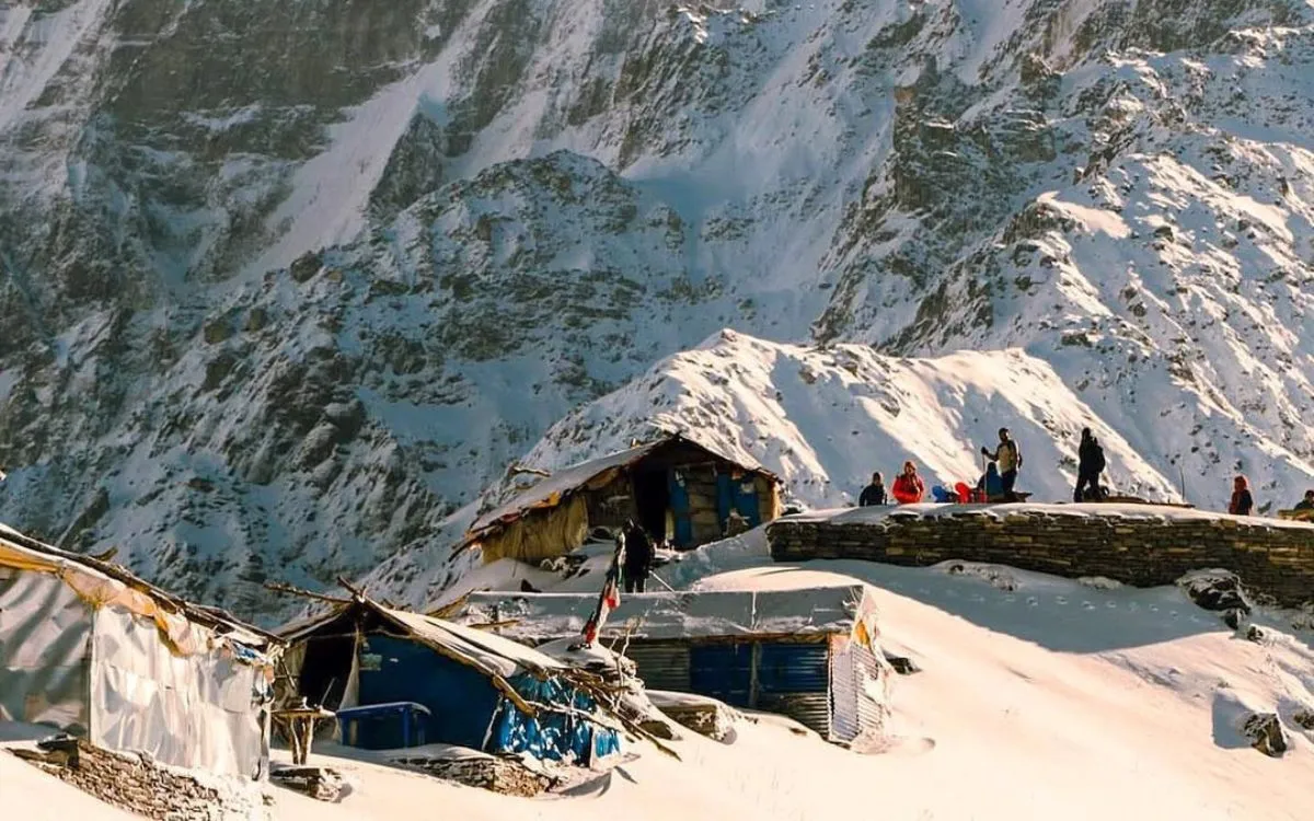 Dramatic view of Machapuchare (Fishtail Mountain) towering over small mountain lodges with snow-covered slopes