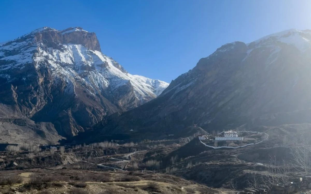A white monastery perched on a ridge in the stark arid valley landscape of Upper Mustang, Nepal