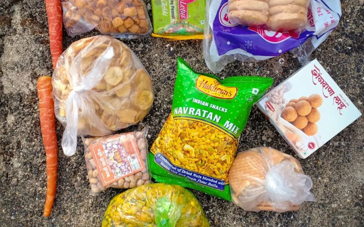 Packaged Indian snacks including Navratan mix, nuts, and bread on ground
