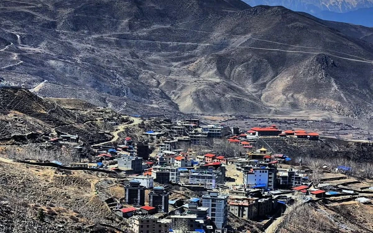 Aerial view of Manang village with red-roofed buildings on an arid hillside on the Annapurna Circuit