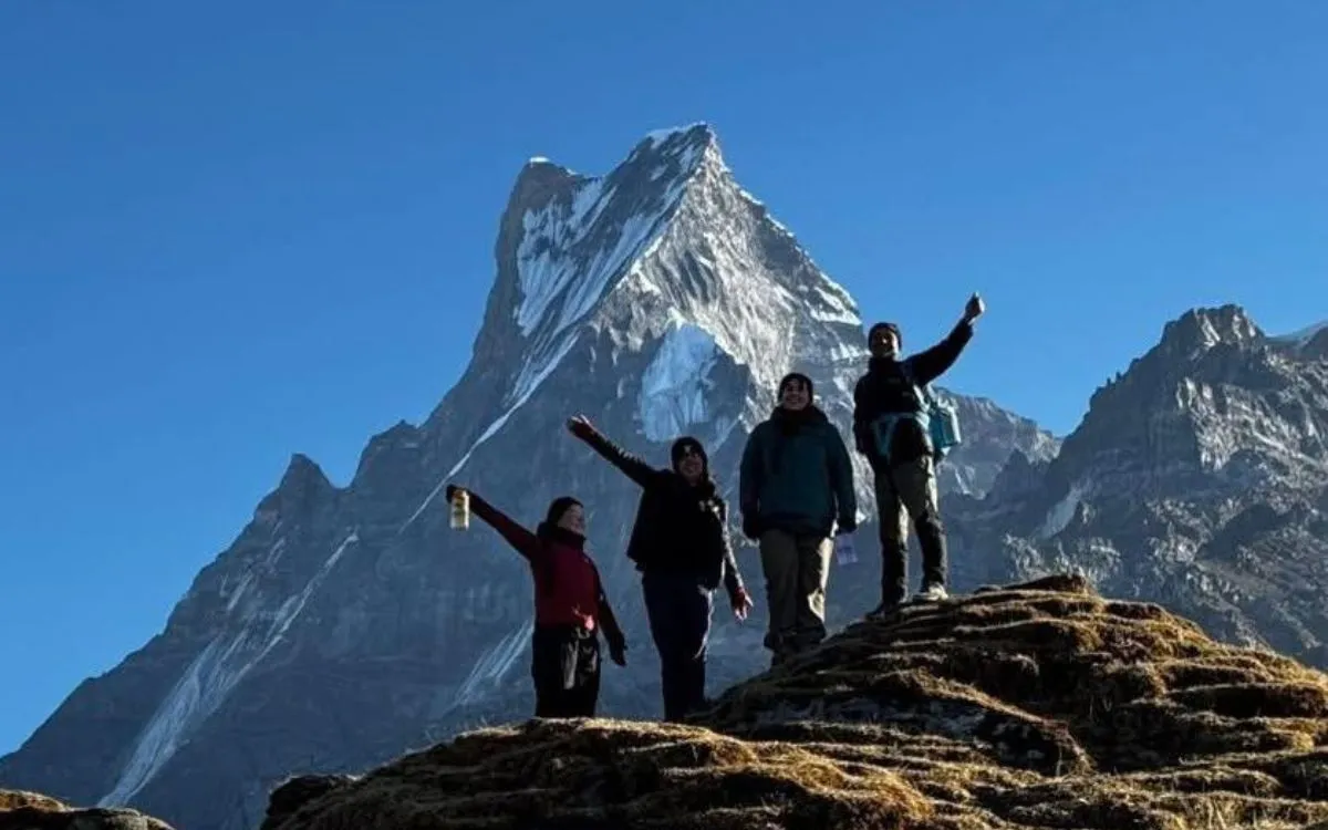 Trekkers celebrating at viewpoint with Machapuchare mountain behind them