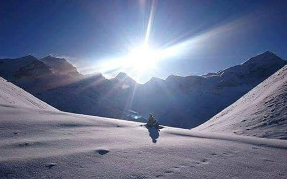 Trekker crossing a sunlit snow pass on the Annapurna Circuit